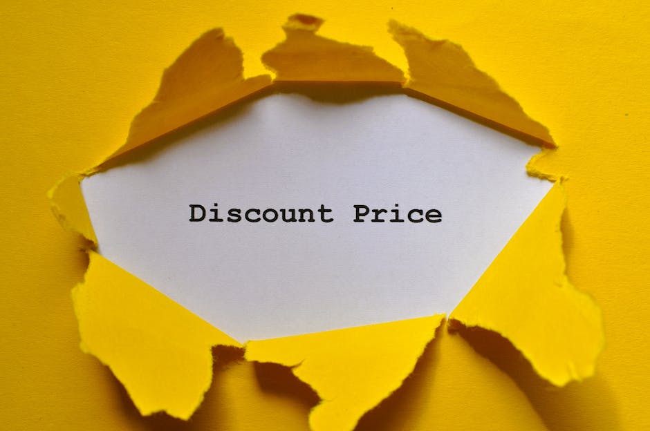 A torn piece of yellow paper reveals a white interior with the words 'Discount Price' typed in black. The paper's edges are irregular and jagged, indicating it has been ripped open. The background is a solid yellow surface that matches the outer part of the torn paper, creating a striking contrast with the white message area. The overall scene emphasizes a promotional or value-focused message, which could relate to alternative waste disposal or special offers from a rubbish removal service like Rubbish Removal Notting Hill. There are no other objects or environmental details visible in the image, and the lighting is uniform, highlighting the texture of the torn paper and the clarity of the text inside.